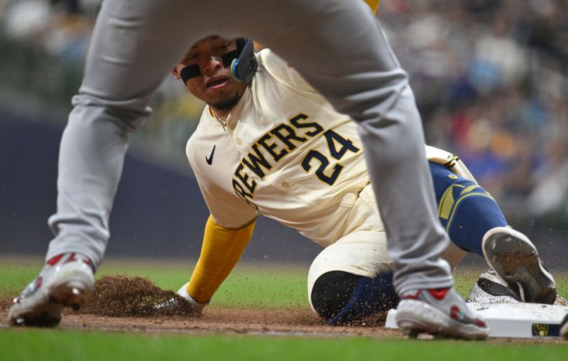 May 10, 2024; Milwaukee, Wisconsin, USA; Milwaukee Brewers shortstop Willy Adames (27) slides in safely to third base ahead of the tag of St. Louis Cardinals third base Nolan Arenado (28) in the seventh inning at American Family Field. Mandatory Credit: Michael McLoone-USA TODAY Sports