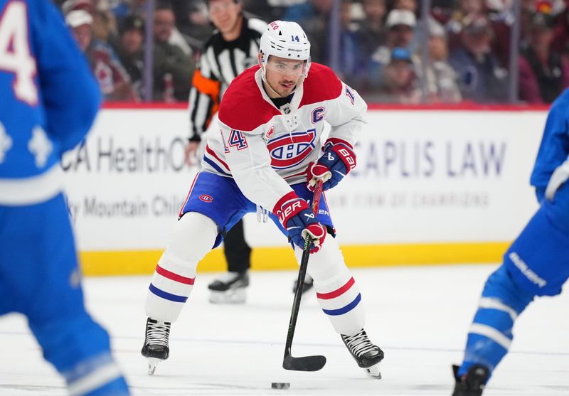 Nov 29, 2025; Denver, Colorado, USA; Montreal Canadiens center Nick Suzuki (14) controls the puck in the first period against the Colorado Avalanche at Ball Arena. Mandatory Credit: Ron Chenoy-Imagn Images