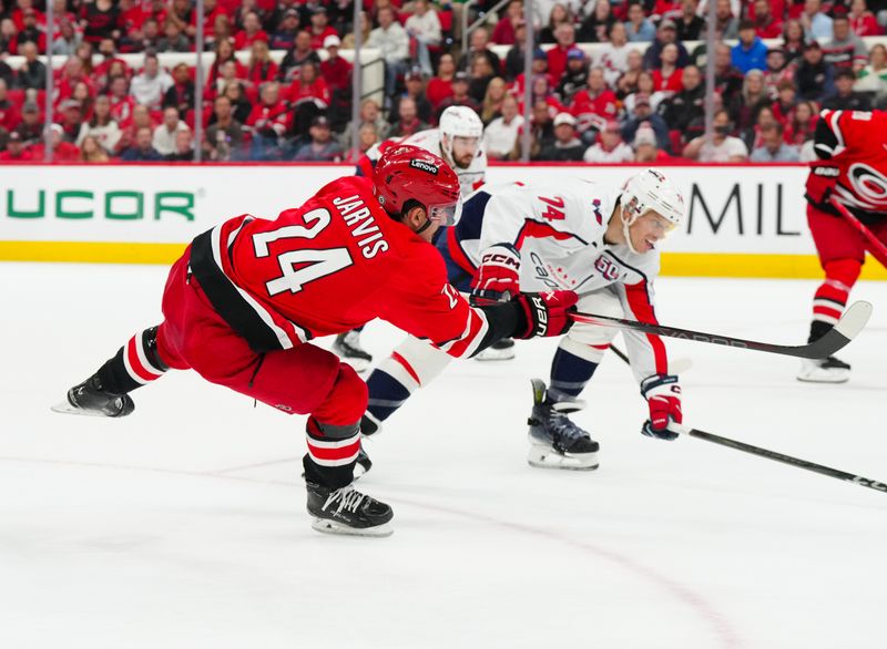 Apr 2, 2025; Raleigh, North Carolina, USA;  Carolina Hurricanes center Seth Jarvis (24) shoots past Washington Capitals defenseman John Carlson (74) during the first period at Lenovo Center. Mandatory Credit: James Guillory-Imagn Images