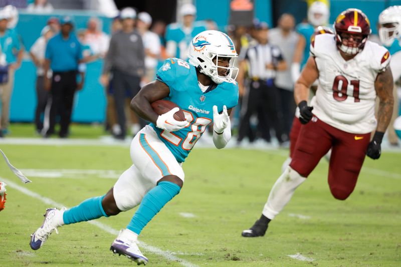 Miami Dolphins running back De'Von Achane (28) runs with the football during the first half of a preseason NFL football game against the Washington Commanders, Saturday, Aug. 17, 2024, in Miami Gardens, Fla. (AP Photo/Rhona Wise)