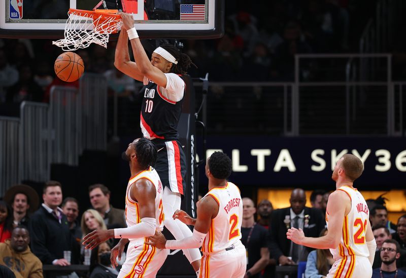 ATLANTA, GEORGIA - MARCH 27:  Moses Brown #10 of the Portland Trail Blazers dunks against Bruno Fernando #24 and Trent Forrest #2 of the Atlanta Hawks during the third quarter at State Farm Arena on March 27, 2024 in Atlanta, Georgia.  NOTE TO USER: User expressly acknowledges and agrees that, by downloading and/or using this photograph, user is consenting to the terms and conditions of the Getty Images License Agreement.  (Photo by Kevin C. Cox/Getty Images)