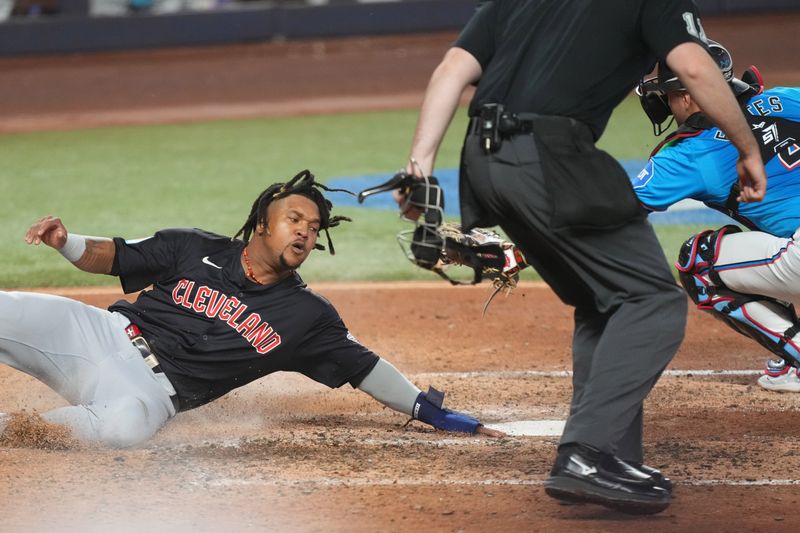 Jun 9, 2024; Miami, Florida, USA; Cleveland Guardians third baseman José Ramírez (11) slides in safe at home plate as Miami Marlins catcher Nick Fortes (4) awaits the throw in the sixth inning at loanDepot Park. Mandatory Credit: Jim Rassol-USA TODAY Sports