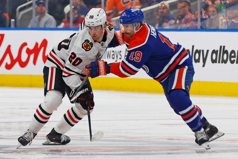 Nov 1, 2025; Edmonton, Alberta, CAN; Edmonton Oilers forward Adam Henrique (19) and Chicago Blackhawks forward Ryan Greene (20) battles for position during the second period at Rogers Place. Mandatory Credit: Perry Nelson-Imagn Images