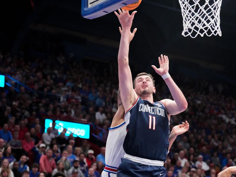 Dec 2, 2025; Lawrence, Kansas, USA; UConn Huskies forward Alex Karaban (11) shoots a layup as Kansas Jayhawks guard Tre White (3) defends during the first half of the game at Allen Fieldhouse. Mandatory Credit: Denny Medley-Imagn Images