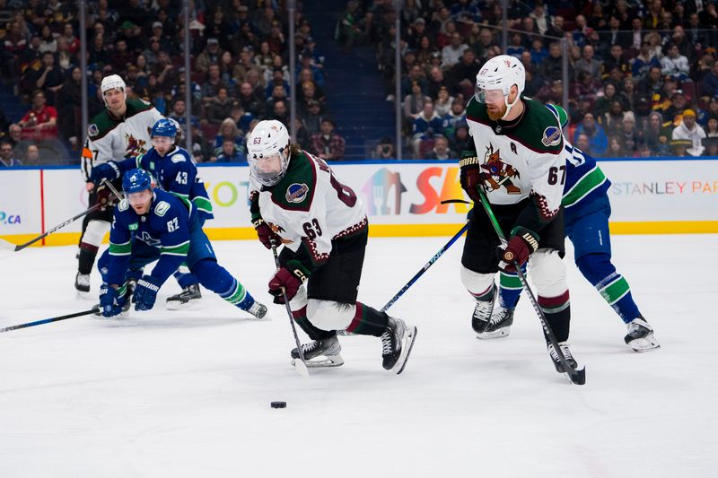 Jan 18, 2024; Vancouver, British Columbia, CAN; Arizona Coyotes forward Lawson Crouse (67) watches forward Matias Maccelli (63) handles the puck against the Vancouver Canucks in the second period at Rogers Arena. Mandatory Credit: Bob Frid-USA TODAY Sports