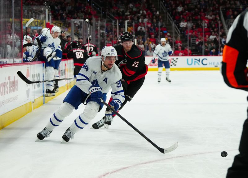 Mar 24, 2024; Raleigh, North Carolina, USA;  Toronto Maple Leafs center Auston Matthews (34) skates with the puck past Carolina Hurricanes defenseman Brett Pesce (22) during the second period at PNC Arena. Mandatory Credit: James Guillory-USA TODAY Sports