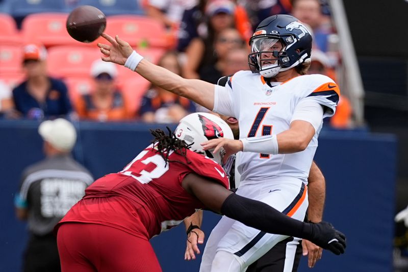 Denver Broncos quarterback Zach Wilson, right, gets hit by Arizona Cardinals linebacker Jesse Luketa, left, as Wilson gets off a pass during the first half of a preseason NFL football game Sunday, Aug. 25, 2024, in Denver. (AP Photo/David Zalubowski)