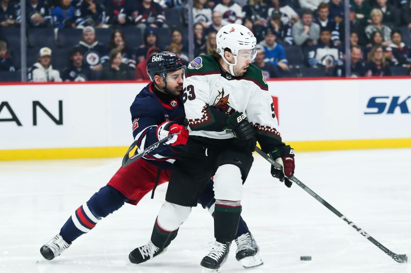 Nov 18, 2023; Winnipeg, Manitoba, CAN;  Winnipeg Jets defenseman Dylan DeMelo (2) and Arizona Coyotes forward Michael Carcone (53) fight for the puck during the first period at Canada Life Centre. Mandatory Credit: Terrence Lee-USA TODAY Sports