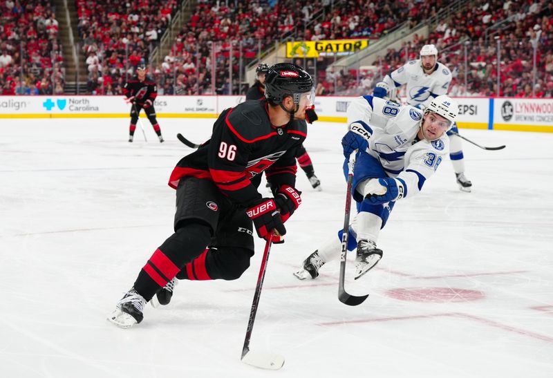 Oct 11, 2024; Raleigh, North Carolina, USA;  Carolina Hurricanes center Jack Roslovic (96) skates withy the puck past Tampa Bay Lightning left wing Brandon Hagel (38) during the third period at PNC Arena. Mandatory Credit: James Guillory-Imagn Images