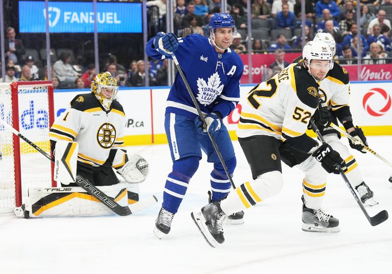 Nov 5, 2024; Toronto, Ontario, CAN; Toronto Maple Leafs center John Tavares (91) battles with Boston Bruins defenseman Andrew Peeke (52) in front of goaltender Jeremy Swayman (1) during the first period at Scotiabank Arena. Mandatory Credit: Nick Turchiaro-Imagn Imagess