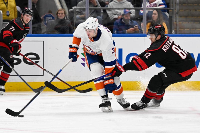 Mar 19, 2024; Elmont, New York, USA; New York Islanders defenseman Adam Pelech (3) and Carolina Hurricanes center Jesperi Kotkaniemi (82) battle for the puck during the third period at UBS Arena. Mandatory Credit: Dennis Schneidler-USA TODAY Sports