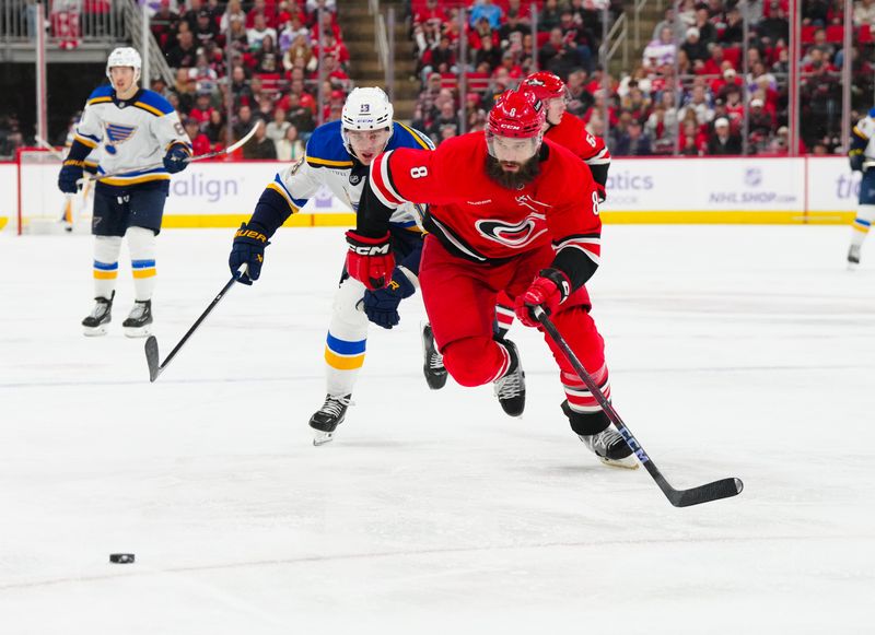 Nov 17, 2024; Raleigh, North Carolina, USA;  Carolina Hurricanes defenseman Brent Burns (8) and St. Louis Blues right wing Alexey Toropchenko (13) chase after the puck during the second period at Lenovo Center. Mandatory Credit: James Guillory-Imagn Images