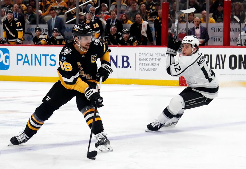 Feb 18, 2024; Pittsburgh, Pennsylvania, USA;  Pittsburgh Penguins defenseman Erik Karlsson (65) moves the puck as Los Angeles Kings left wing Trevor Moore (12) chases during the third period at PPG Paints Arena.  Los Angeles won 2-1.Mandatory Credit: Charles LeClaire-USA TODAY Sports