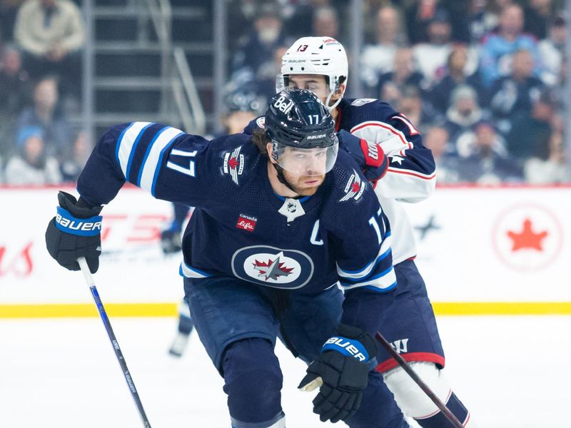 Jan 9, 2024; Winnipeg, Manitoba, CAN; Winnipeg Jets forward Adam Lowry (17) and Columbus Blue Jackets forward Johnny Gaudreau (13) skate after the puck during the first period at Canada Life Centre. Mandatory Credit: Terrence Lee-USA TODAY Sports