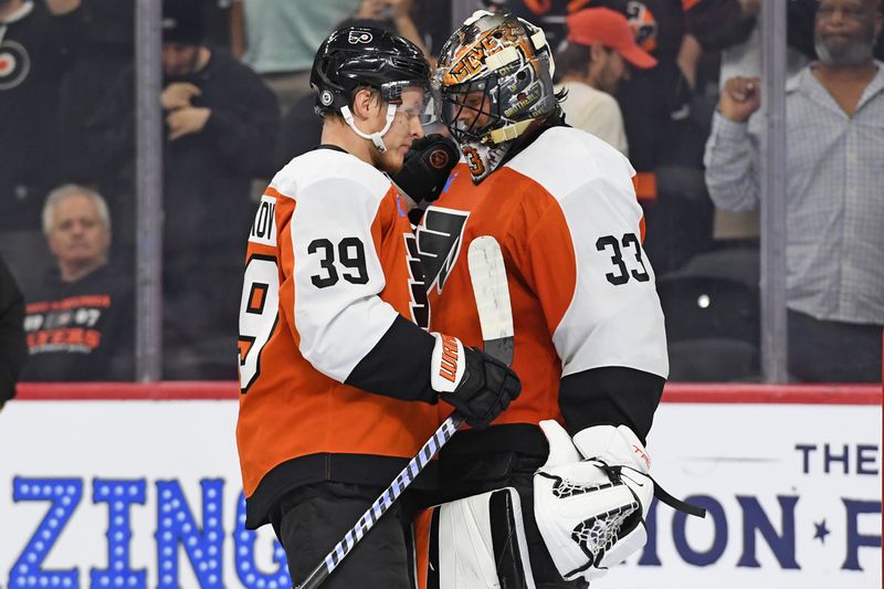 Sep 26, 2024; Philadelphia, Pennsylvania, USA; Philadelphia Flyers right wing Matvei Michkov (39) and goaltender Samuel Ersson (33) celebrate win against the New York Islanders at Wells Fargo Center. Mandatory Credit: Eric Hartline-Imagn Images