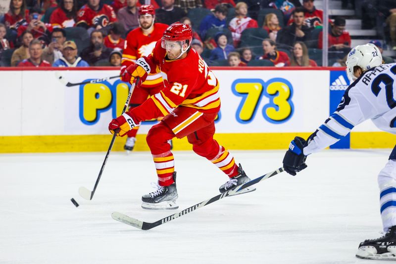 Feb 19, 2024; Calgary, Alberta, CAN; Calgary Flames center Kevin Rooney (21) shoots the puck against the Winnipeg Jets during the second period at Scotiabank Saddledome. Mandatory Credit: Sergei Belski-USA TODAY Sports