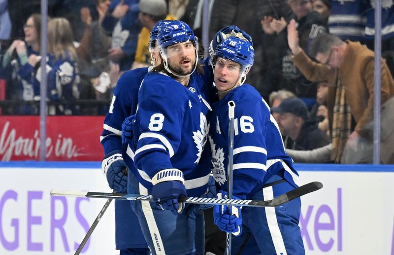 Nov 24, 2024; Toronto, Ontario, CAN;  Toronto Maple Leafs forward Mitch Marner (16) celebrates with defenseman Chris Tanev (8) after scoring a goal against the Utah Hockey Club in the second period at Scotiabank Arena. Mandatory Credit: Dan Hamilton-Imagn Images