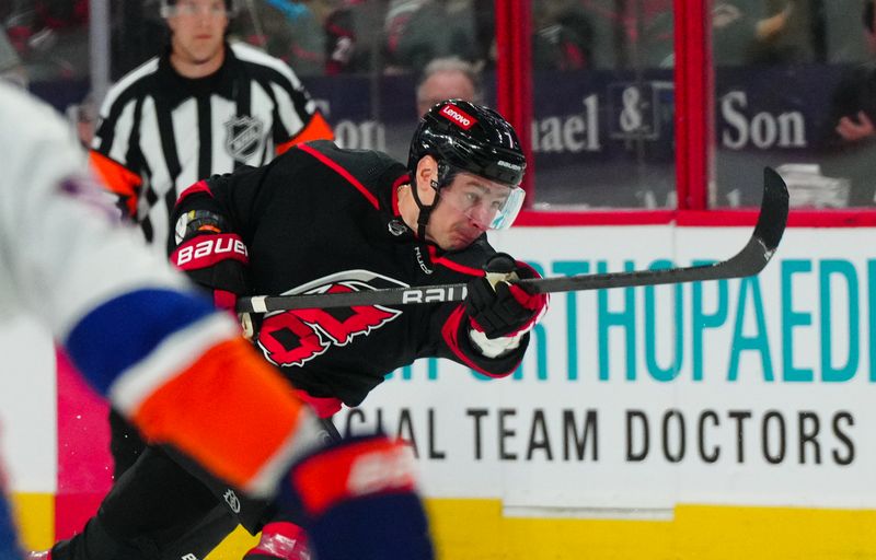 Apr 20, 2024; Raleigh, North Carolina, USA; Carolina Hurricanes defenseman Dmitry Orlov (7) takes a shot against the New York Islanders during the first period in game one of the first round of the 2024 Stanley Cup Playoffs at PNC Arena. Mandatory Credit: James Guillory-USA TODAY Sports