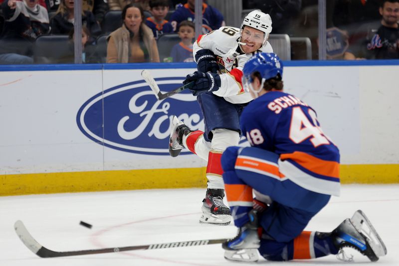 Mar 28, 2026; Elmont, New York, USA; Florida Panthers left wing Matthew Tkachuk (19) takes a shot against New York Islanders defenseman Matthew Schaefer (48) during the third period at UBS Arena. Mandatory Credit: Brad Penner-Imagn Images