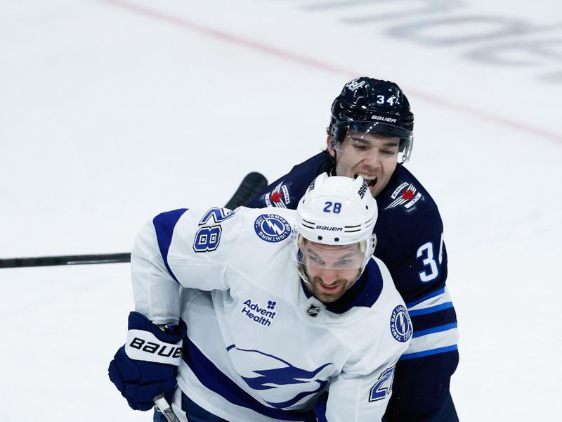 Mar 5, 2026; Winnipeg, Manitoba, CAN;  Winnipeg Jets defenseman Ville Heinola (34) jostles for position with Tampa Bay Lightning forward Zemgus Gingensons (28) during the third period at Canada Life Centre. Mandatory Credit: Terrence Lee-Imagn Images