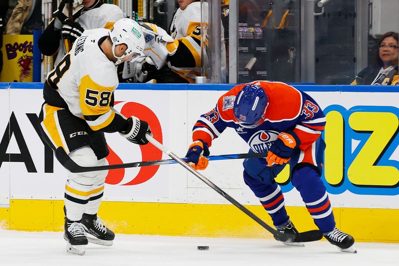 Oct 25, 2024; Edmonton, Alberta, CAN; Pittsburgh Penguins defensemen Kris Letang (58) and Edmonton Oilers forward Victor Arvidsson (33) battle for a loose puck during the first period at Rogers Place. Mandatory Credit: Perry Nelson-Imagn Images