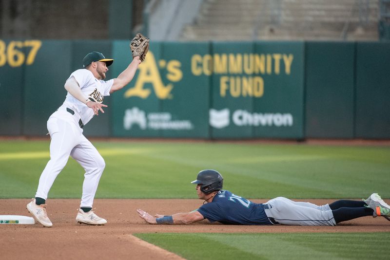 Jun 4, 2024; Oakland, California, USA; Seattle Mariners shortstop Dylan Moore (25) steals second base against the Oakland Athletics shortstop Max Schuemann (12) during the fourth inning at Oakland-Alameda County Coliseum. Mandatory Credit: Ed Szczepanski-USA TODAY Sports