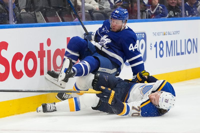 Oct 24, 2024; Toronto, Ontario, CAN; Toronto Maple Leafs defenseman Morgan Rielly (44) and St. Louis Blues forward Oskar Sundqvist (70) collide at the boards during the second period at Scotiabank Arena. Mandatory Credit: John E. Sokolowski-Imagn Images