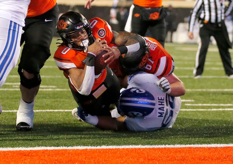 Nov 25, 2023; Stillwater, Oklahoma, USA;  Oklahoma State's Ollie Gordon II (0) scores against BYU's Atunaisa Mahe (62) during second half  at Boone Pickens Stadium. Mandatory Credit: Sarah Phipps-USA TODAY Sports