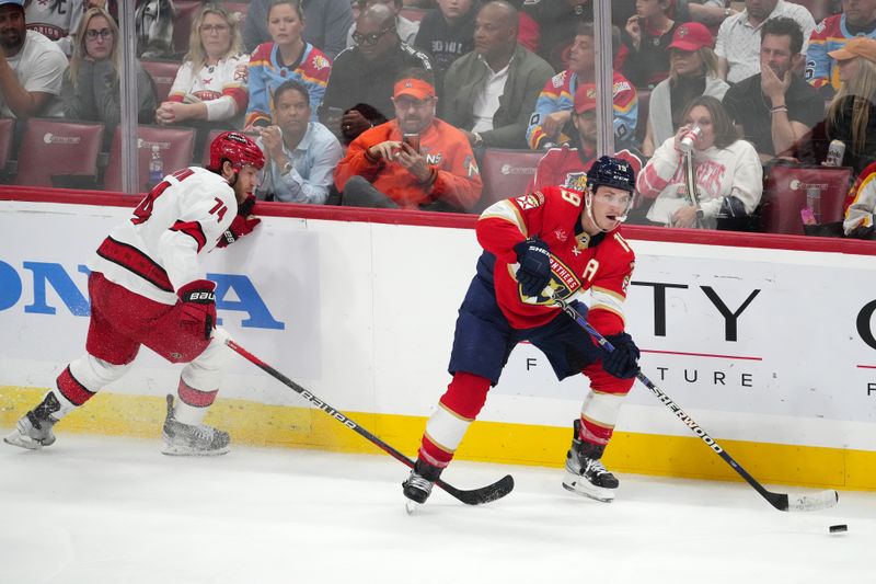 Nov 10, 2023; Sunrise, Florida, USA; Florida Panthers left wing Matthew Tkachuk (19) passes the puck away from Carolina Hurricanes defenseman Jaccob Slavin (74) during the third period at Amerant Bank Arena. Mandatory Credit: Jasen Vinlove-USA TODAY Sports