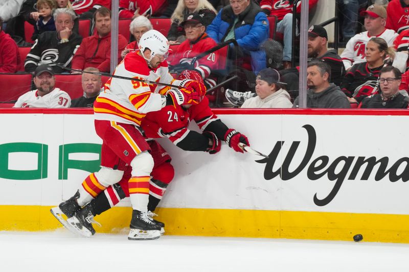 Nov 30, 2025; Raleigh, North Carolina, USA;  Calgary Flames defenseman Mackenzie Weegar (52) checks Carolina Hurricanes center Seth Jarvis (24) during the first period at Lenovo Center. Mandatory Credit: James Guillory-Imagn Images