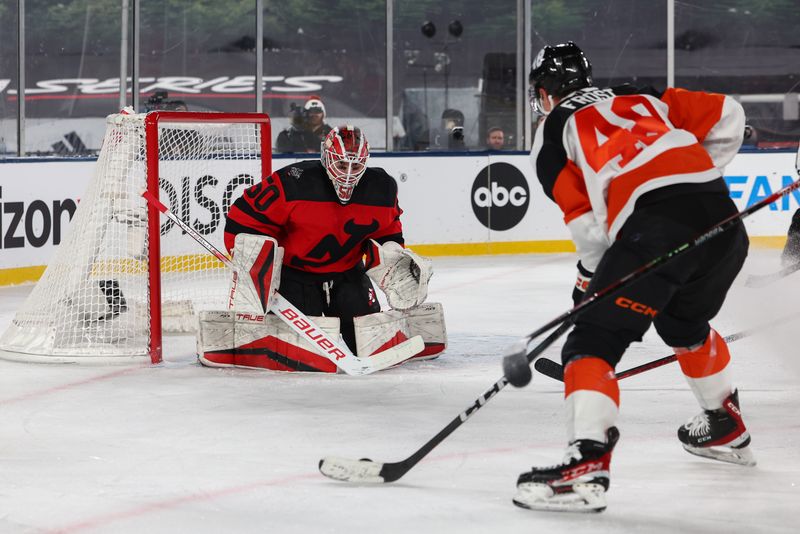 Feb 17, 2024; East Rutherford, New Jersey, USA; New Jersey Devils goaltender Nico Daws (50) defends his net against Philadelphia Flyers center Morgan Frost (48) during the third period in a Stadium Series ice hockey game at MetLife Stadium. Mandatory Credit: Ed Mulholland-USA TODAY Sports