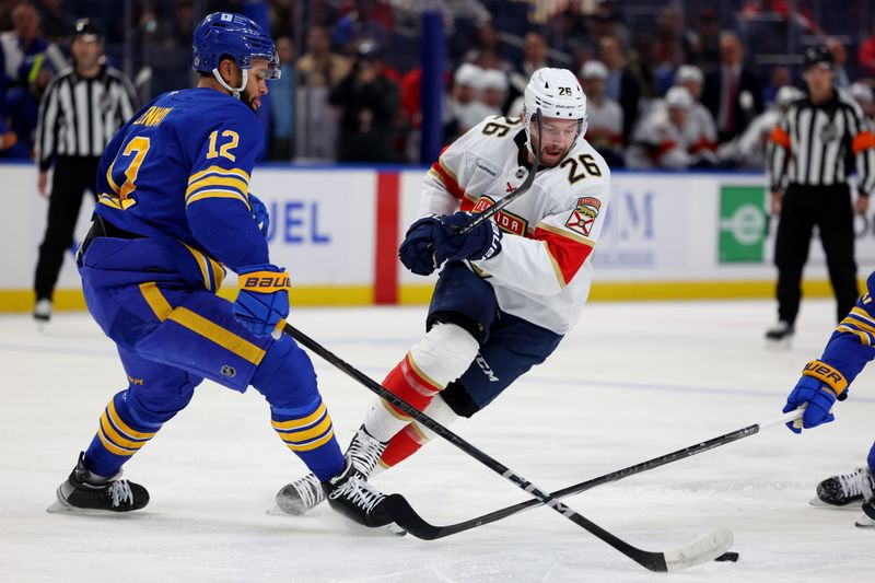 Oct 28, 2024; Buffalo, New York, USA;  Buffalo Sabres left wing Jordan Greenway (12) and Florida Panthers defenseman Uvis Balinskis (26) go after a loose puck during the first period at KeyBank Center. Mandatory Credit: Timothy T. Ludwig-Imagn Images