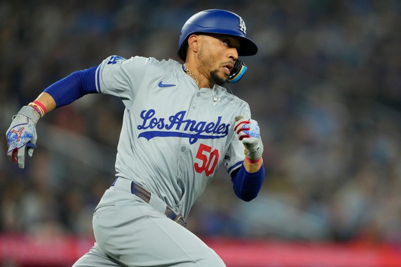 Apr 28, 2024; Toronto, Ontario, CAN; Los Angeles Dodgers shortstop Mookie Betts (50) runs to first base on his double against the Toronto Blue Jays during the eighth inning at Rogers Centre. Mandatory Credit: John E. Sokolowski-USA TODAY Sports