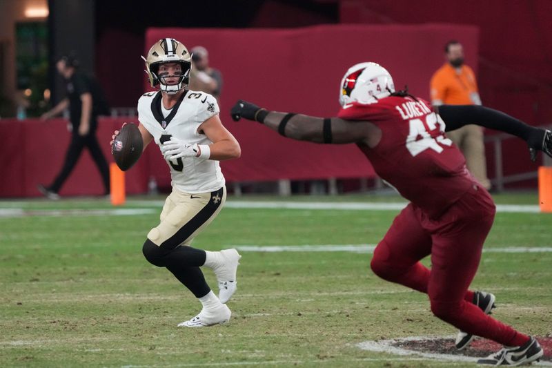 New Orleans Saints quarterback Jake Haener (3) scrambles against Arizona Cardinals linebacker Jesse Luketa (43) in the first half of a preseason NFL football game, Saturday, Aug. 10, 2024, in Glendale, Ariz. (AP Photo/Rick Scuteri)