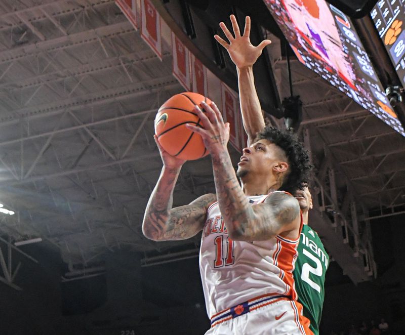 Feb 4, 2023; Clemson, South Carolina, USA; Clemson guard Brevin Galloway (11) scores near Miami guard Isaiah Wong (2) during the second half at Littlejohn Coliseum in Clemson, S.C. Saturday, Feb. 4, 2023.   Mandatory Credit: Ken Ruinard-USA TODAY Sports