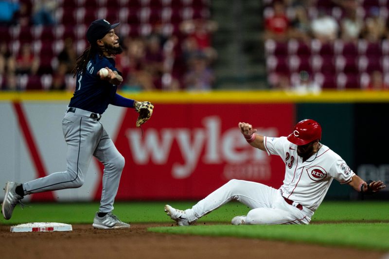 Sep 6, 2023; Cincinnati, Ohio, USA; Seattle Mariners shortstop J.P. Crawford (3) turns a double play as Cincinnati Reds left fielder Nick Martini (23) slides into second in the eighth inning of the MLB baseball game between the Cincinnati Reds and the Seattle Mariners at Great American Ball Park. Mandatory Credit: Albert Cesare-USA TODAY Sports