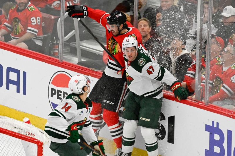 Apr 7, 2024; Chicago, Illinois, USA;  Chicago Blackhawks defenseman Jaycob Megna (24) and Minnesota Wild defenseman Declan Chisholm (47) hit the glass during the first period at United Center. Mandatory Credit: Matt Marton-USA TODAY Sports