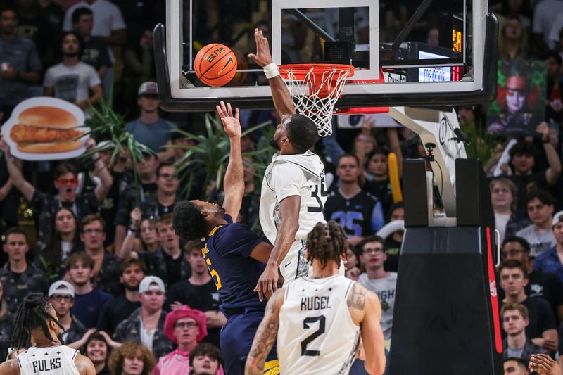 Feb 14, 2026; Orlando, Florida, USA; UCF Knights forward Devan Cambridge (35) blocks a shot by West Virginia Mountaineers forward DJ Thomas (5) during the second half at Addition Financial Arena. Mandatory Credit: Mike Watters-Imagn Images