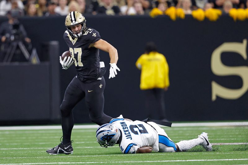 New Orleans Saints tight end Foster Moreau (87) is tripped up by Carolina Panthers cornerback Michael Jackson (2) during an NFL football game, Sunday, Sept. 8, 2024, in New Orleans. (AP Photo/Tyler Kaufman)