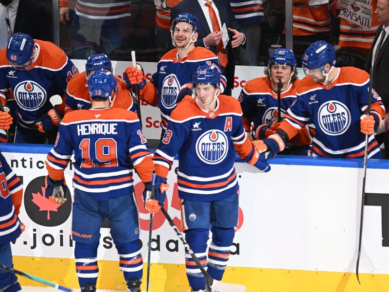 Mar 22, 2025; Edmonton, Alberta, CAN;  Edmonton Oilers centre Adam Lowry (19) along with Oilers centre Ryan Nugent-Hopkins (93) celebrate a hat trick at the Oilers bench during the third period at Rogers Place. Mandatory Credit: Walter Tychnowicz-Imagn Images