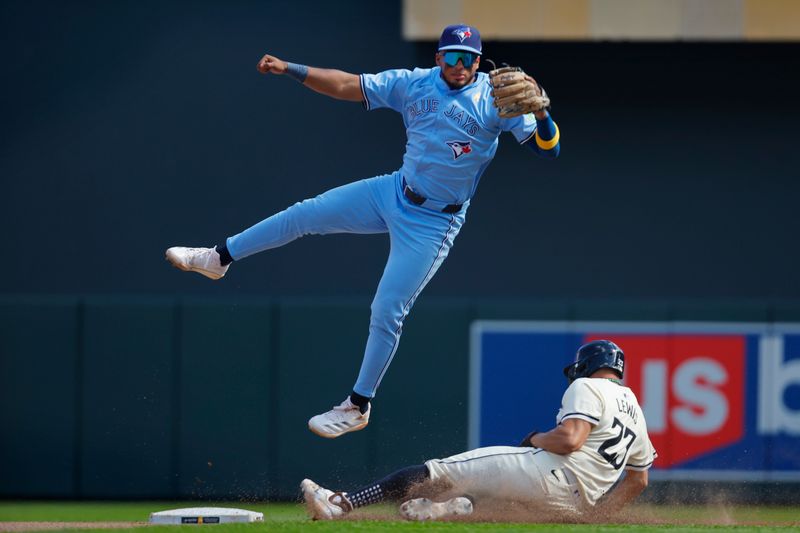 Sep 1, 2024; Minneapolis, Minnesota, USA; Toronto Blue Jays shortstop Leonardo Jimenez (49) leaps on an errant throw from the third baseman as Minnesota Twins third baseman Royce Lewis (23) slides into second base and advances to third in the seventh inning at Target Field. Mandatory Credit: Bruce Kluckhohn-USA TODAY Sports