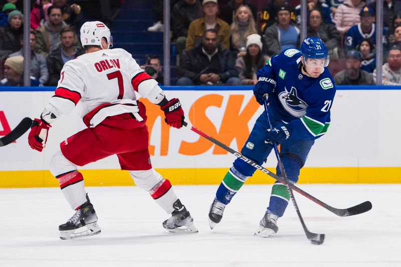 Dec 9, 2023; Vancouver, British Columbia, CAN; Vancouver Canucks forward Nils Hoglander (21) shoots in front of Carolina Hurricanes defenseman Dmitry Orlov (7) in the first period at Rogers Arena. Mandatory Credit: Bob Frid-USA TODAY Sports