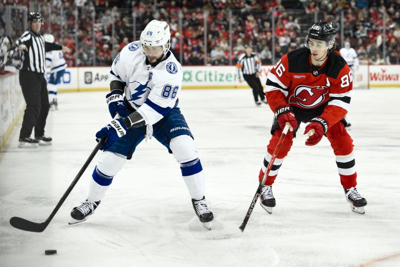 Feb 25, 2024; Newark, New Jersey, USA; Tampa Bay Lightning right wing Nikita Kucherov (86) skates with the puck while being defended by New Jersey Devils center Jack Hughes (86) during the first period at Prudential Center. Mandatory Credit: John Jones-USA TODAY Sports