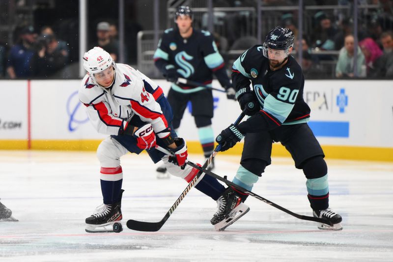 Mar 14, 2024; Seattle, Washington, USA; Washington Capitals defenseman Martin Fehervary (42) and Seattle Kraken left wing Tomas Tatar (90) play the puck during the second period at Climate Pledge Arena. Mandatory Credit: Steven Bisig-USA TODAY Sports