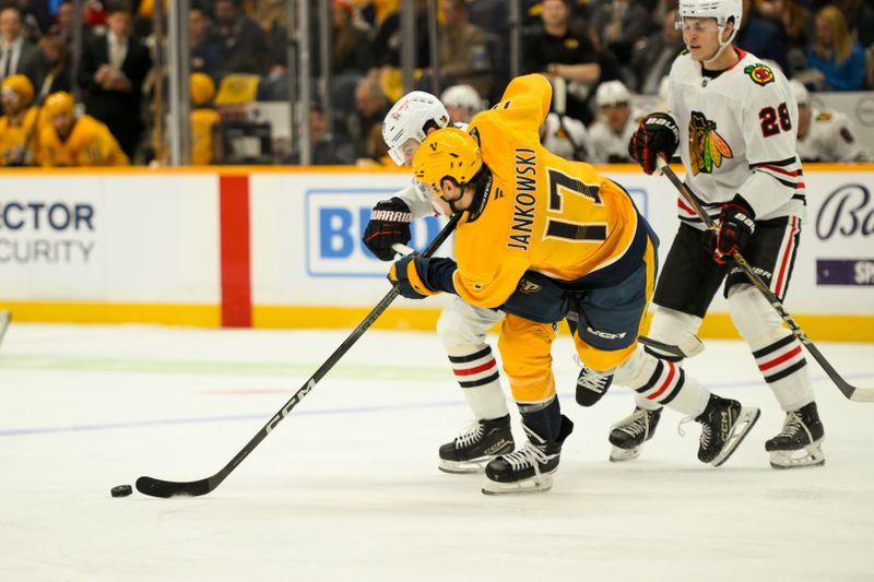 Jan 16, 2025; Nashville, Tennessee, USA;  Nashville Predators center Mark Jankowski (17) and Chicago Blackhawks left wing Lukas Reichel (73) battle for the puck during the first period at Bridgestone Arena. Mandatory Credit: Steve Roberts-Imagn Images