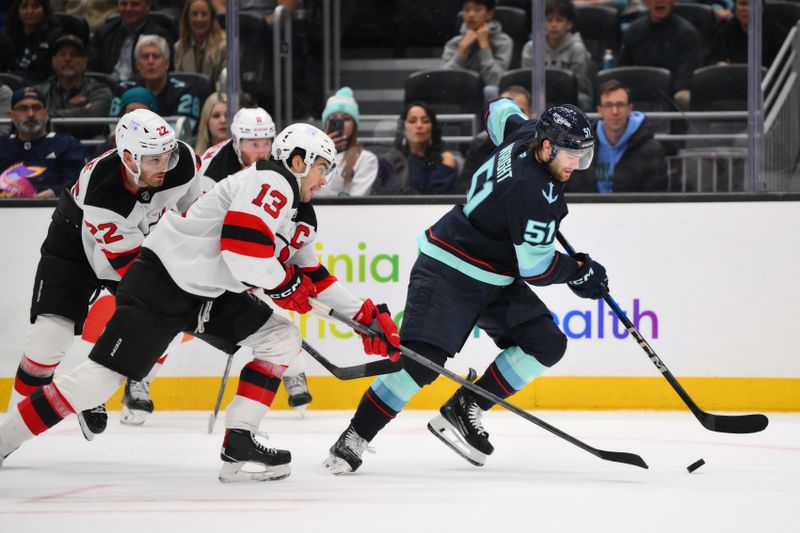 Jan 6, 2025; Seattle, Washington, USA; Seattle Kraken center Shane Wright (51) advances the puck while defended by New Jersey Devils center Nico Hischier (13) during the third period at Climate Pledge Arena. Mandatory Credit: Steven Bisig-Imagn Images