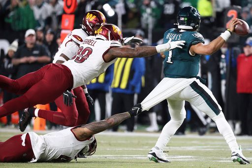 Washington Commanders linebacker Frankie Luvu (4) attempts to take down Philadelphia Eagles quarterback Jalen Hurts (1) during the NFC Championship NFL football game, Sunday, Jan. 26, 2025, in Philadelphia. (AP Photo/Daniel Kucin Jr.)