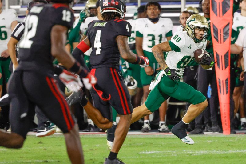 Nov 1, 2024; Boca Raton, Florida, USA;  South Florida Bulls wide receiver Joshua Porter (80) runs the ball past Florida Atlantic Owls defensive back Phillip Dunnam (4) and cornerback Cameron Goggins (12) during the second quarter at FAU Stadium. Mandatory Credit: Reinhold Matay-Imagn Images