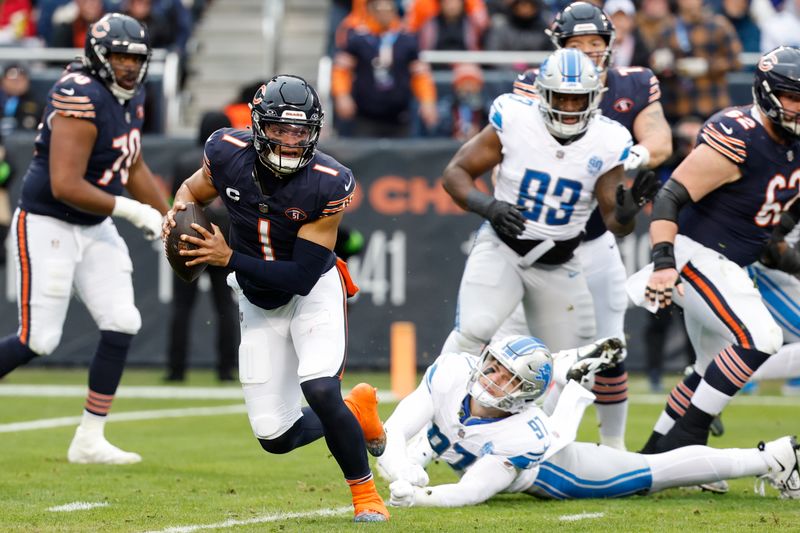 Chicago Bears quarterback Justin Fields (1) runs with the ball past Detroit Lions defensive end Aidan Hutchinson (97) during the first half of an NFL football game, Sunday, Dec. 10, 2023, in Chicago. (AP Photo/Kamil Krzaczynski)