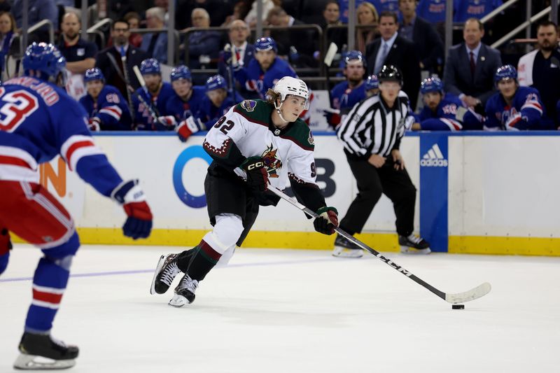 Oct 16, 2023; New York, New York, USA; Arizona Coyotes center Logan Cooley (92) skates with the puck against New York Rangers center Mika Zibanejad (93) during the first period at Madison Square Garden. Mandatory Credit: Brad Penner-USA TODAY Sports